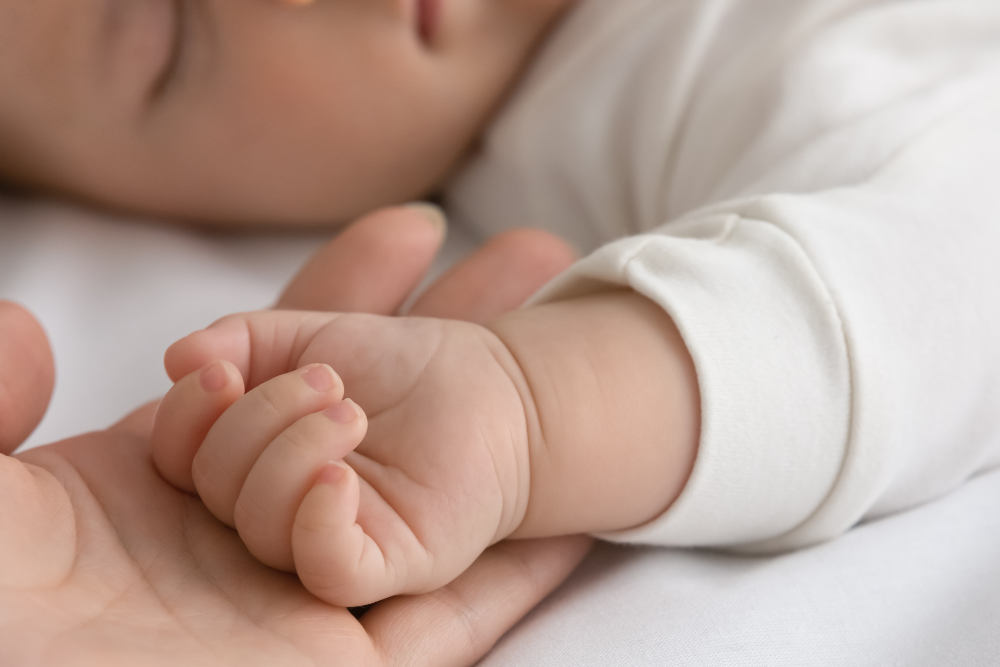 Detail van een babyhandje in de handpalm van een volwassene, symbool van gevoeligheid en de behoefte aan bescherming
