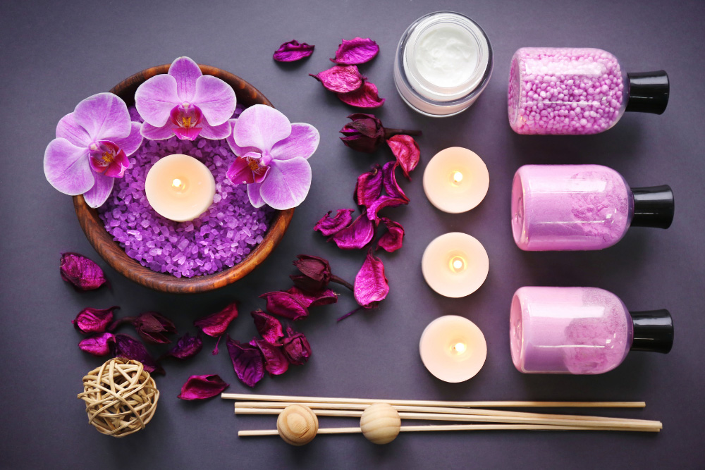 Aromatherapiecompositie met paarse orchideeën, brandende kaarsen, zout en etherische oliën
