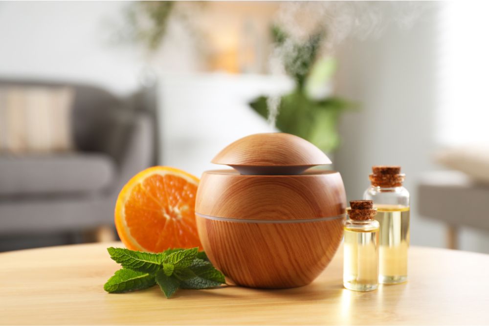 Aromadiffuser van hout met etherische oliën, munt en sinaasappel in een gezellig interieur thuis.