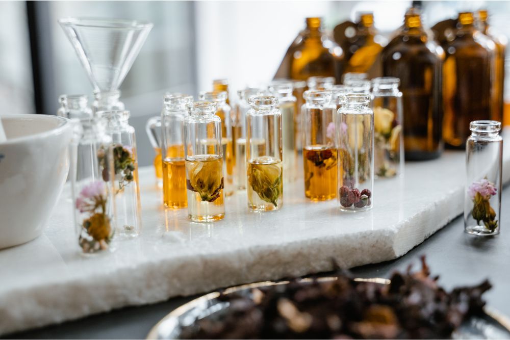 Glazen met verschillende etherische kruidenoliën en verse kruiden op een houten ondergrond – natuurlijke aromatherapie