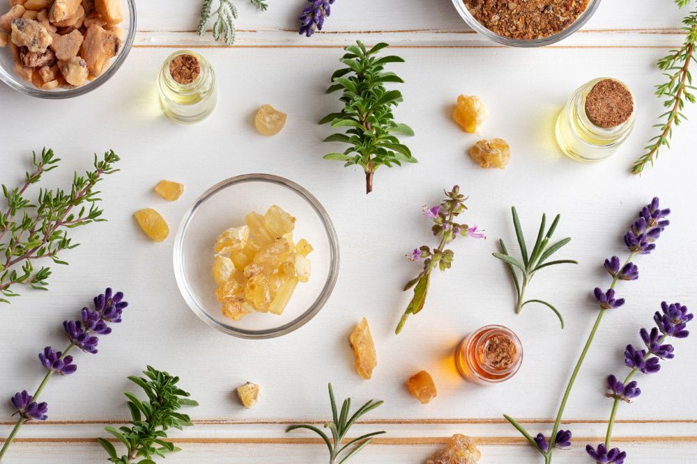 Flesjes met etherische oliën omringd door verse kruiden en bloemen voor aromatherapie