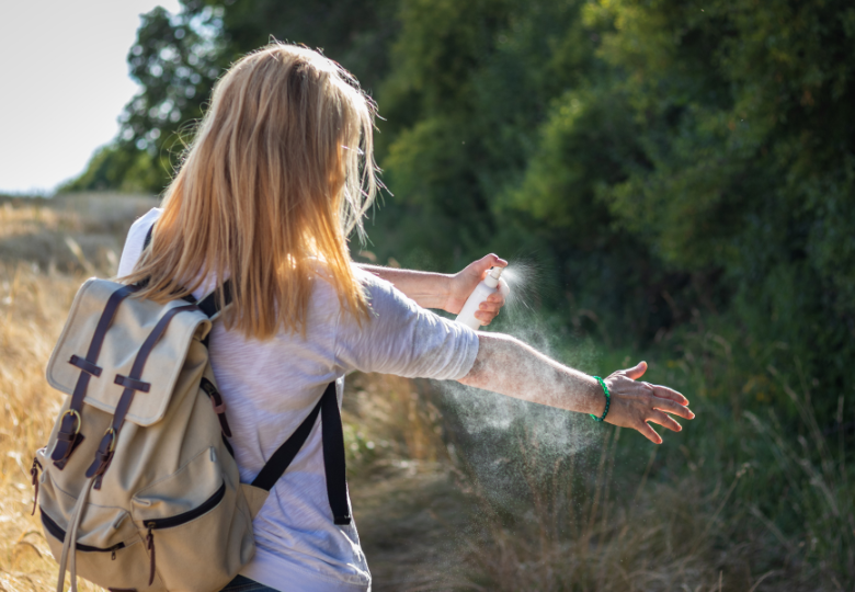 Vrouw buiten die een natuurlijke spray tegen muggen gebruikt