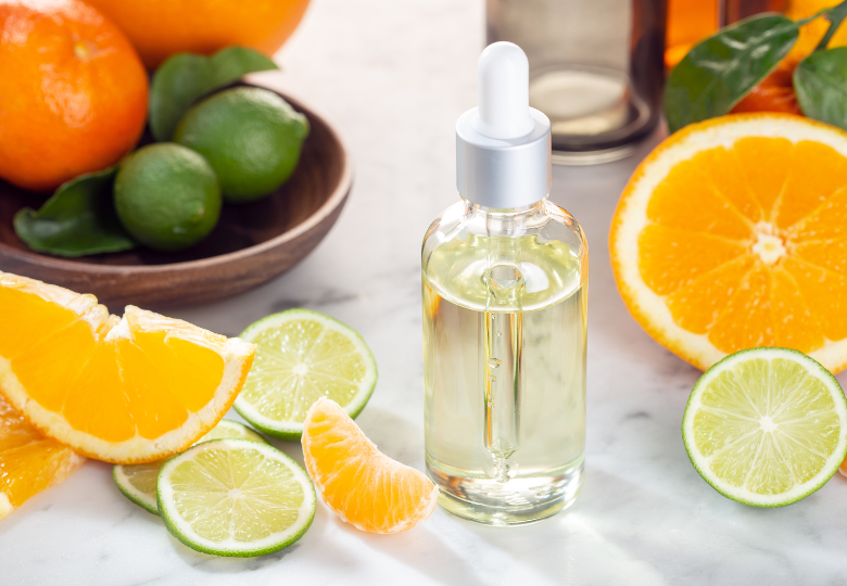 Flesje etherische citroenolie tussen verse schijfjes citrusvruchten – een natuurlijk hulpmiddel om zonder chemie schoon te maken.