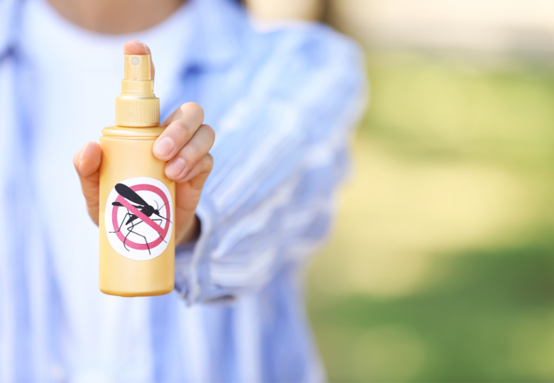Persoon met een afweerspray tegen muggen buiten.